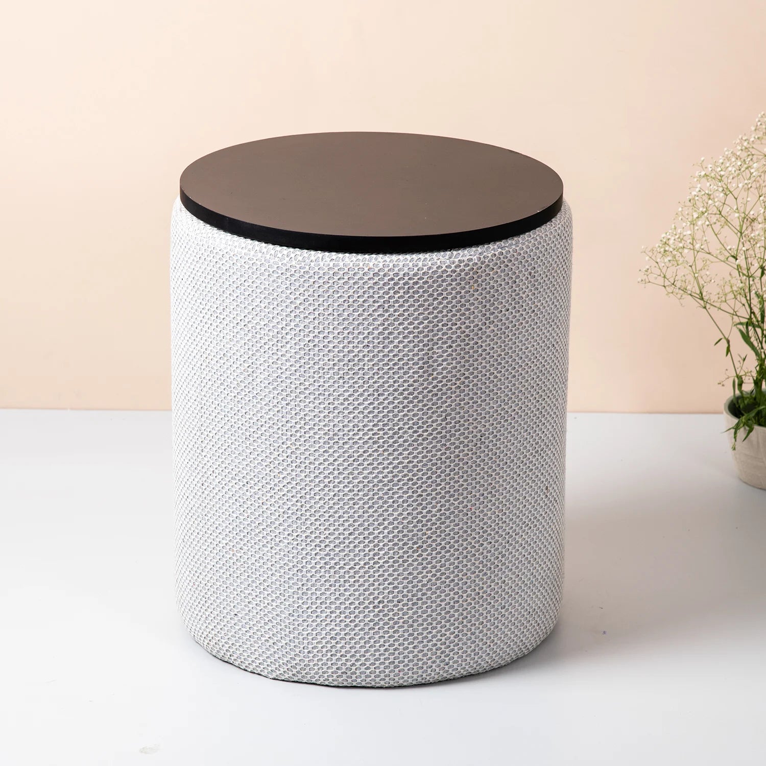 Round side table with woven pattern and wooden top on a plain background