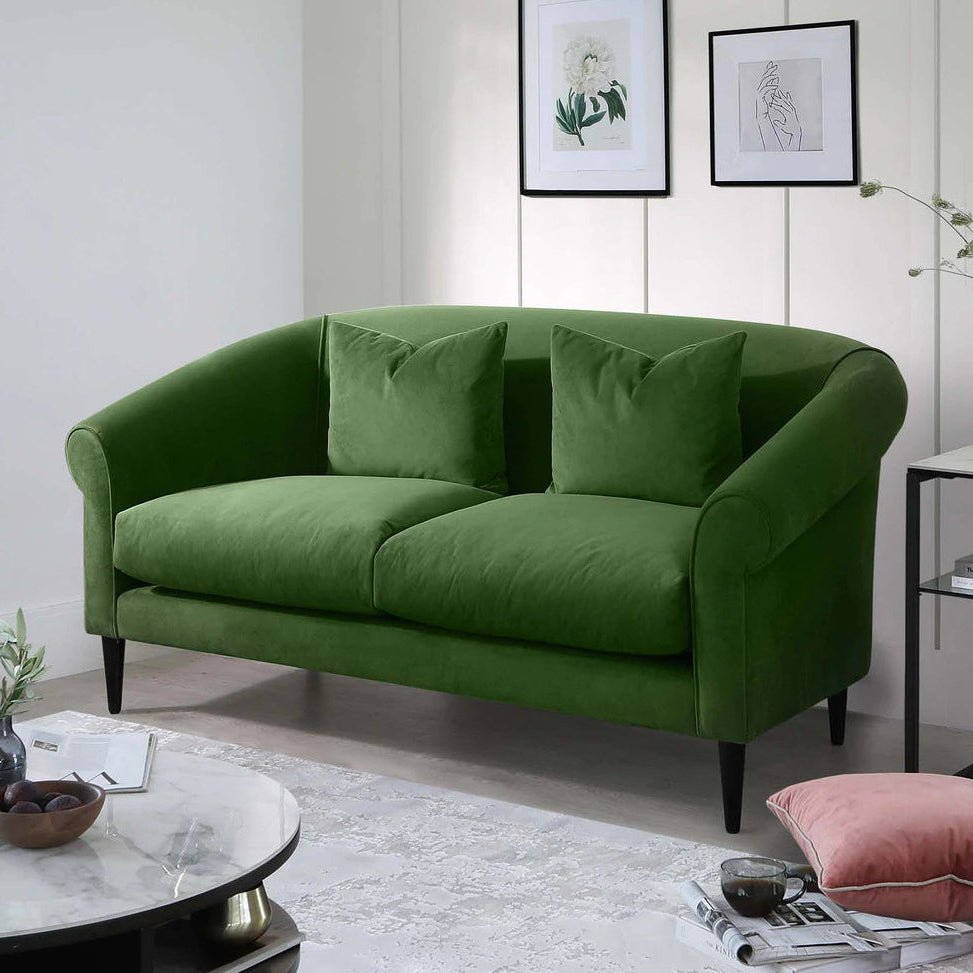 Green sofa in a living room with a white wall and decorative elements.