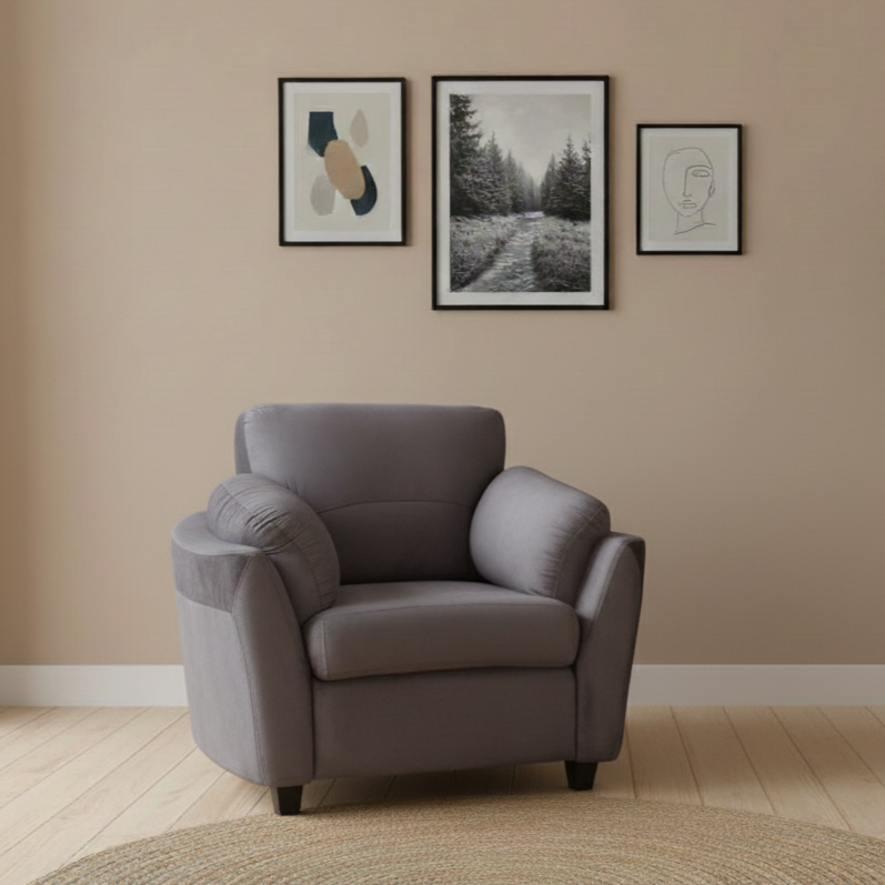 Gray armchair in a room with framed artwork on the wall.
