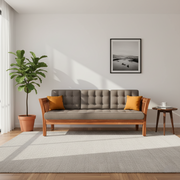 Gray sofa with wooden frame and orange cushions in a living room setting.
