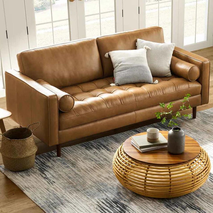 Brown leather sofa in a living room with a wooden coffee table and decorative items.