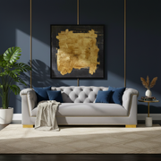 Gray sofa with blue pillows in a room with a gold abstract painting on the wall.