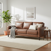 Brown leather sofa in a living room with a plant and side table.