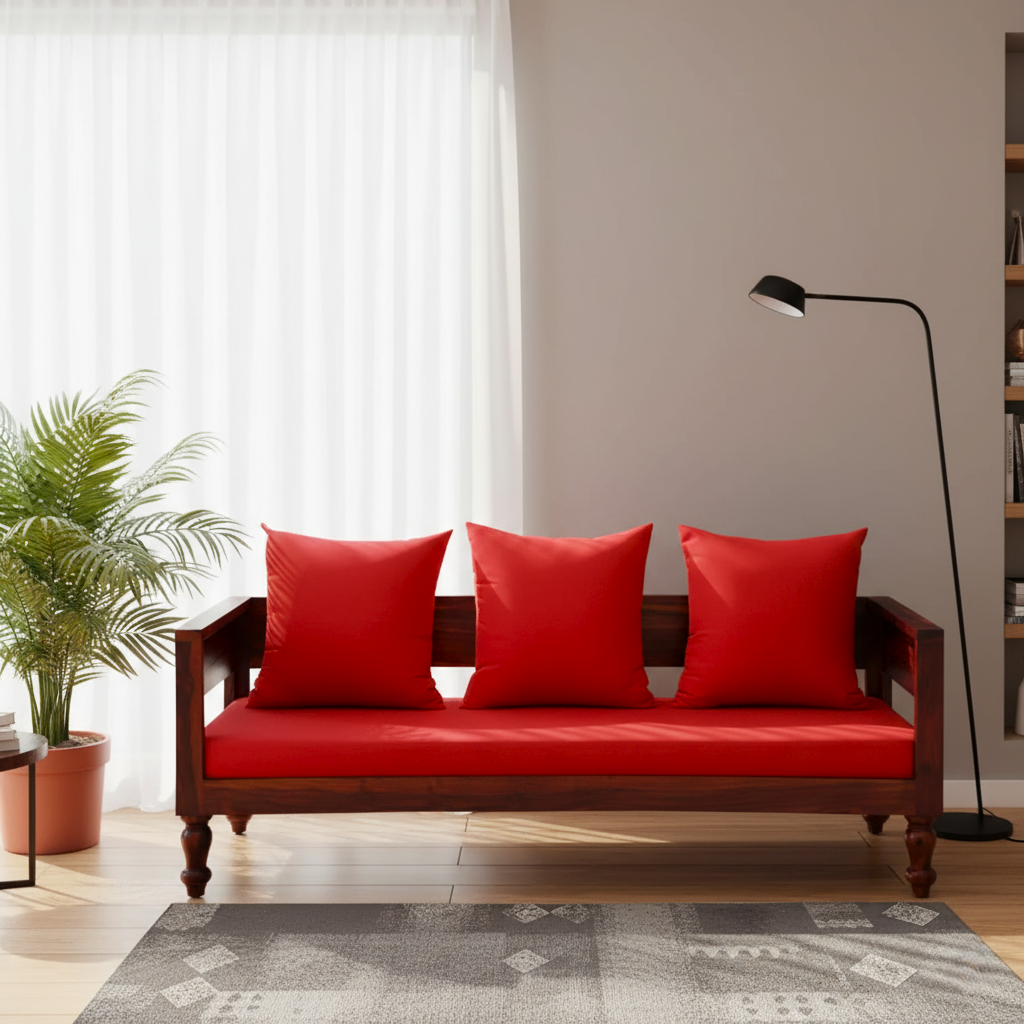 Red sofa with three cushions in a living room setting with a lamp and plant.