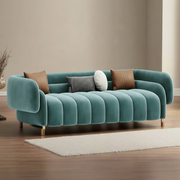 Teal sofa with decorative pillows in a room with beige walls and wooden floor.