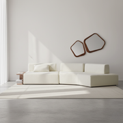 Modern white sofa in a minimalistic room with two wall mirrors.