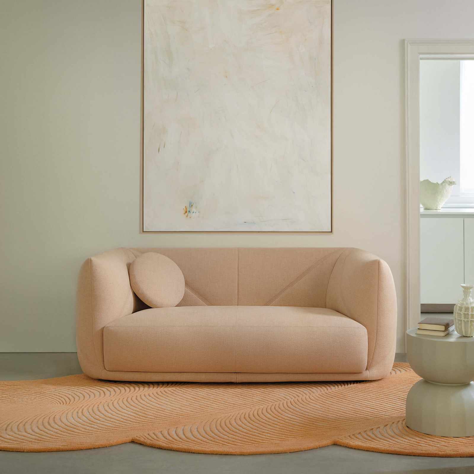 Beige sofa in a modern living room with abstract art and a rug.