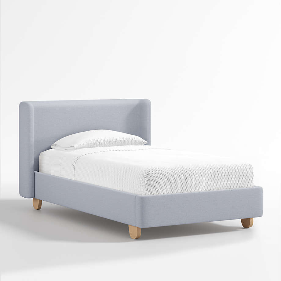 King Size Upholstered Kids Bed features a modern wingback design, soft blue upholstery, rounded oak legs, and stylish comfort with lasting quality