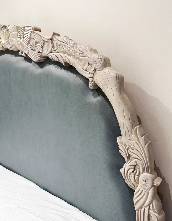 king‑size bed in off‑white with hand-carved Sheesham frame, premium upholstered headboard.