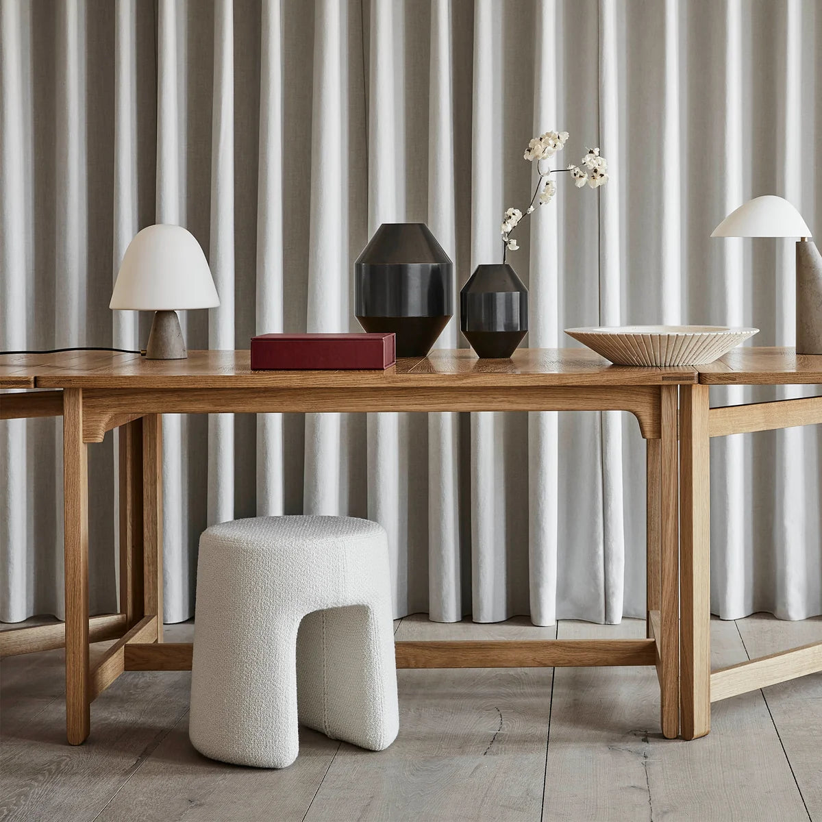 फ़ैब्रिक अपहोल्स्ट्री और लकड़ी के बेस वाला पाउफ़