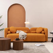 Orange sofa in a modern living room with wooden tables and a lamp.